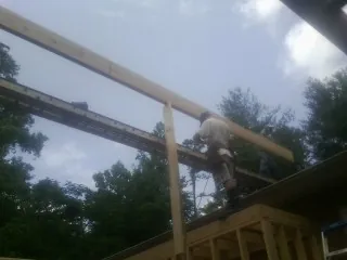 Carpenter setting a ridge beam over a new addition frame — Ice Dam Removal by Roofing Brothers in Orleans